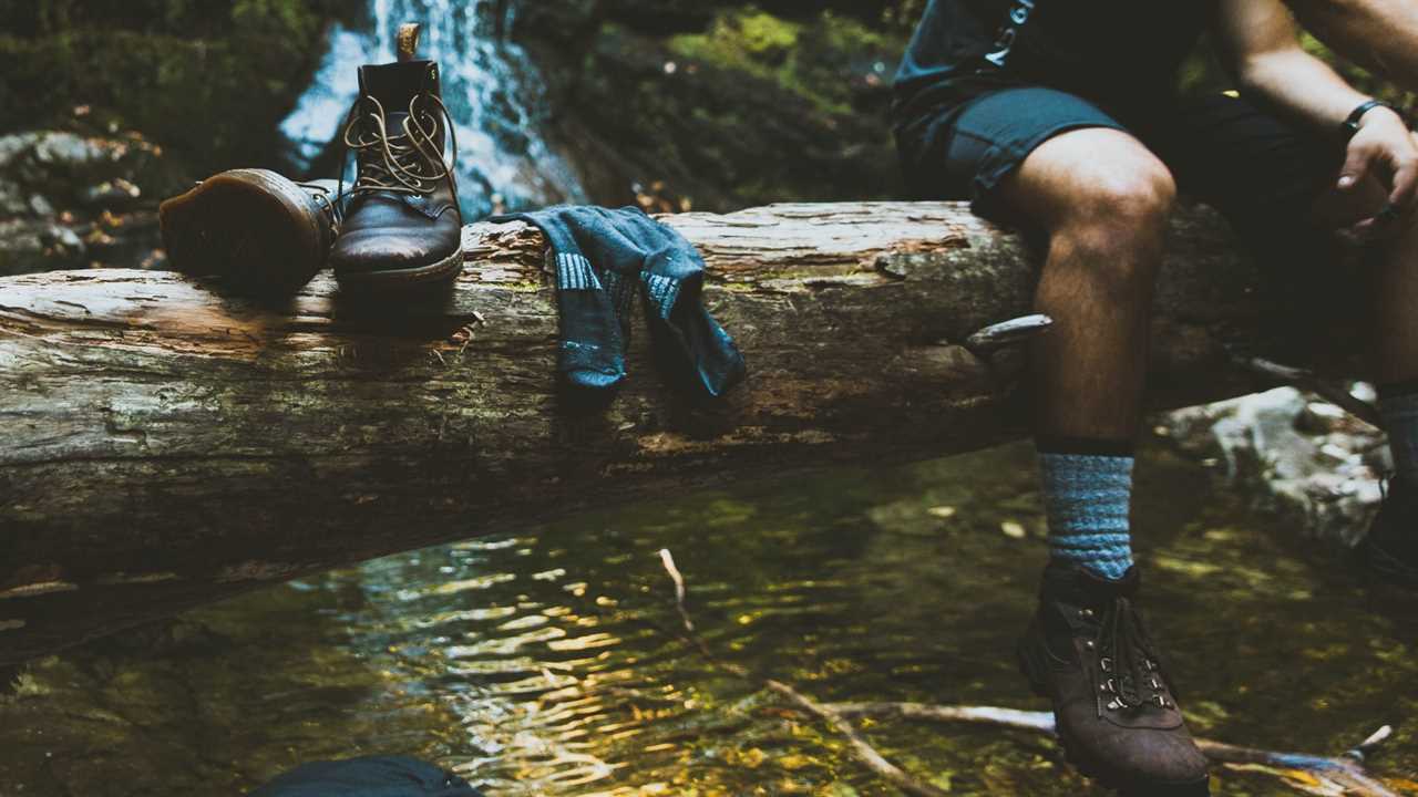 man resting on a log with wool socks