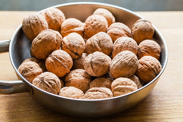 Unshelled walnuts in a metal bowl