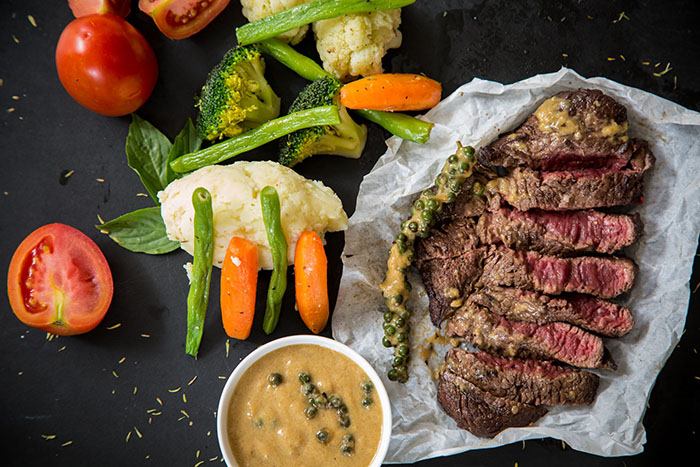 sliced rare steak next to assorted vegetables showing a meal with enough protein