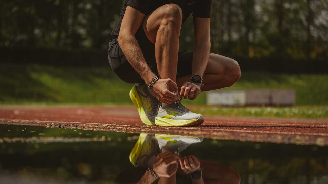 man lacing up waterproof running shoes