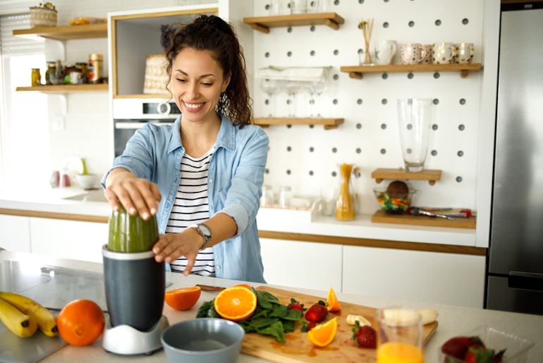 Woman blending a high-fiber green smoothie to have better types of poop