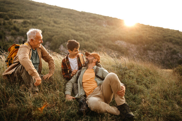 Happy three generations males relaxing on hiking tour