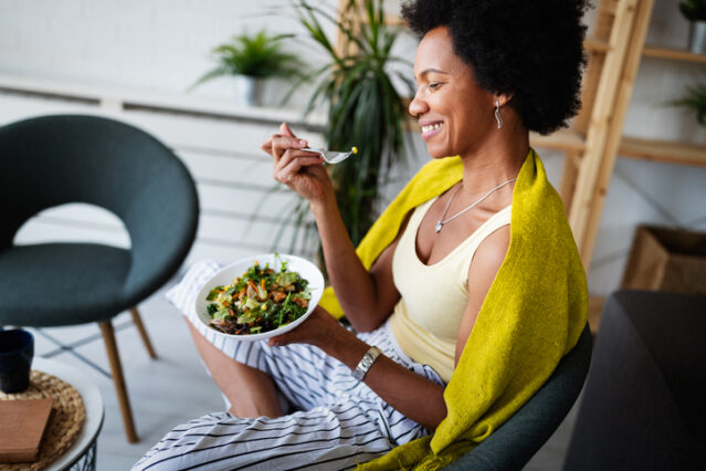 Woman eating vegetable salad at home.