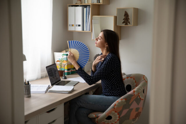 woman fanning cooling herself off from menopause hot flashes