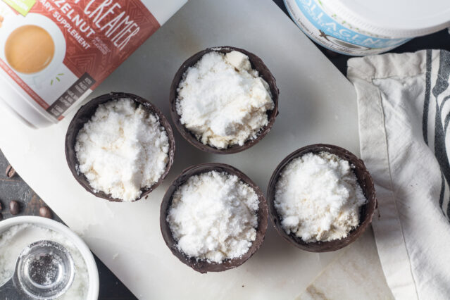 Four halves of chocolate bombs filled with white powder, Primal Kitchen Hazelnut Collagen Fuel.