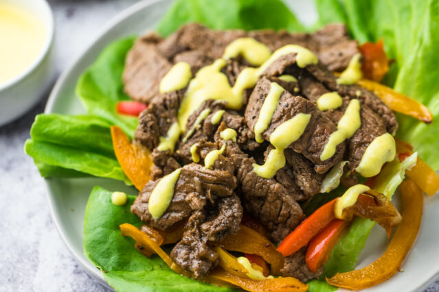 Philly cheesesteak served on lettuce with cheese sauce.