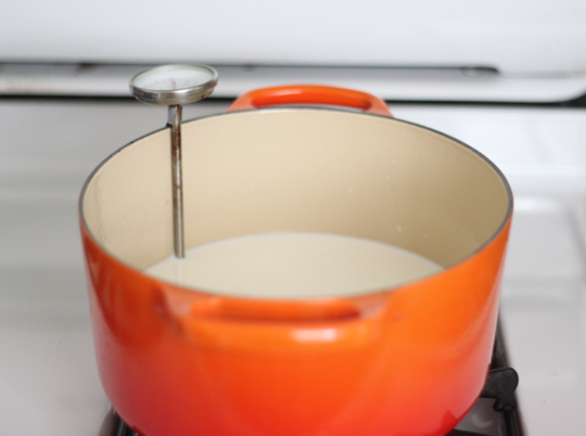 Orange stock pot with milk and food thermometer