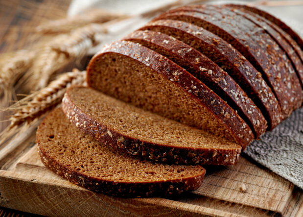 Sliced rye bread with whole grains in background