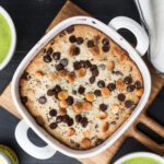 Baked macadamia cookie bars in white baking pan on wooden cutting board, two mugs of Primal Kitchen Matcha Collagen Latte