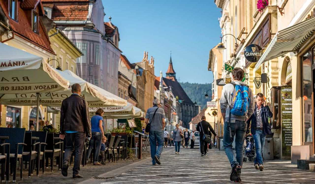 Tourists walking down a narrow old street in Brasoz, Romania