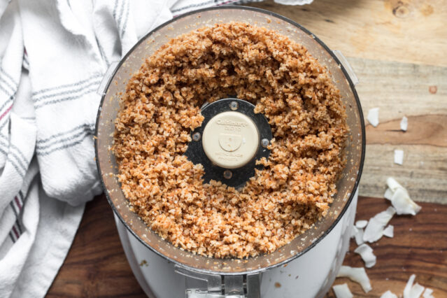 Overhead shot of food processor with coarsely ground coconut. White kitchen towel.