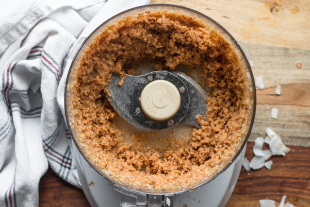 Overhead shot of food processor with finely ground coconut. White kitchen towel.