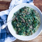 Creamed spinach in white bowl with spoon on wooden background, blue checked napkin.