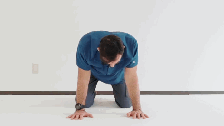 Gif of man in blue polo and gray pants kneeling and doing shoulder circles.