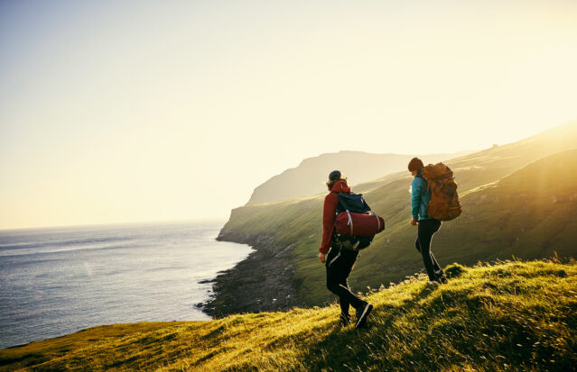 Couple backpacking through the mountains overlooking the sea.