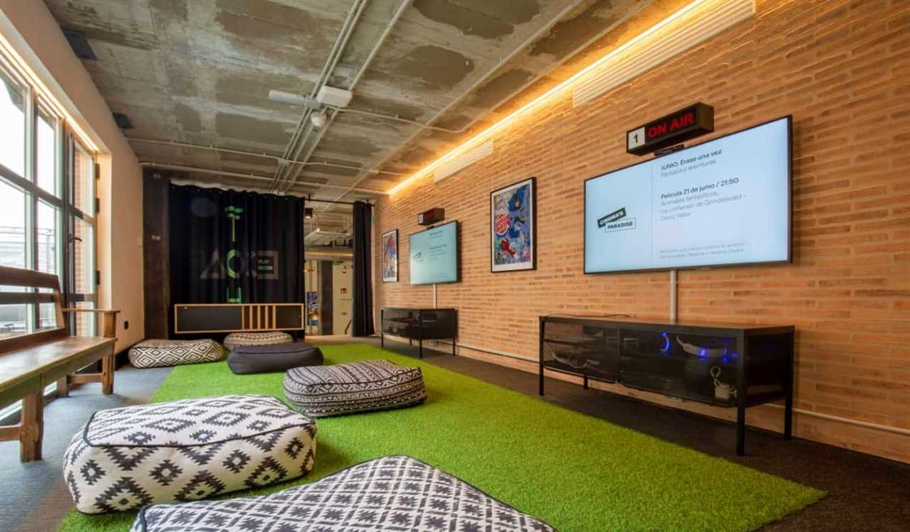 Games room with large flat-screen TVs and lots of bean bag chairs at The Central House Lavapies, a hostel in Madrid, Spain.