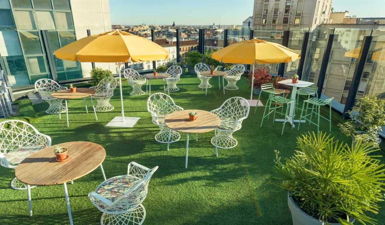 The rooftop terrace of Generator hostel with lots of round tables and chairs, overlooking the rooftops of Madrid, Spain.