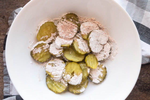 Sliced pickles in a bowl with tapioca starch and spices.