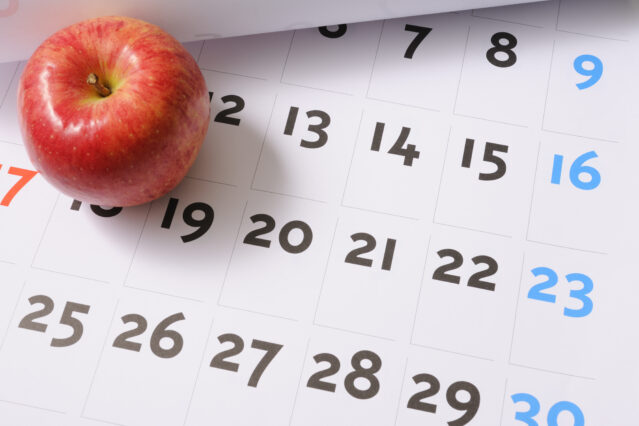 Red apple sitting on calendar.