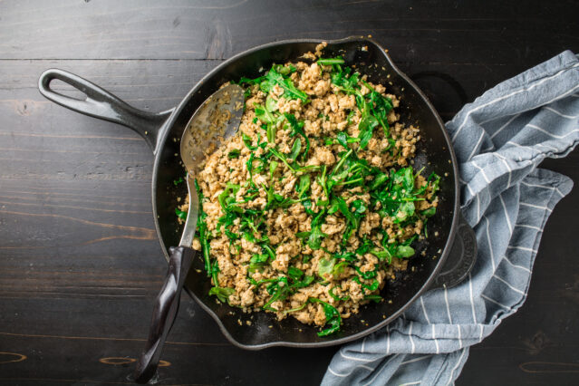 sausage and arugula on stove pan 