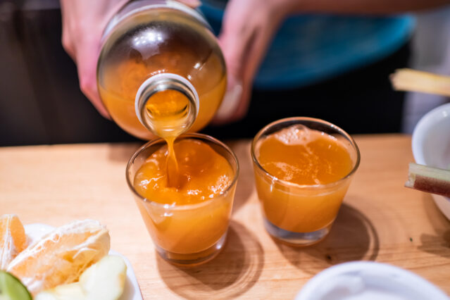 Pouring apple cider vinegar into shot glasses