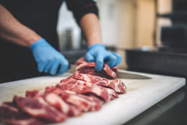 Butcher cuts up slices of meat