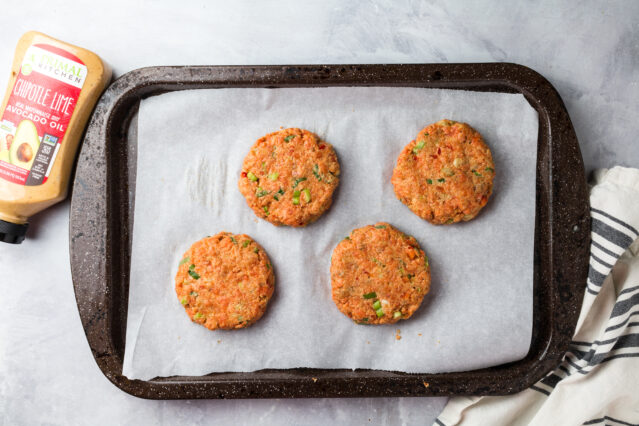 Raw salmon burgers on baking sheet