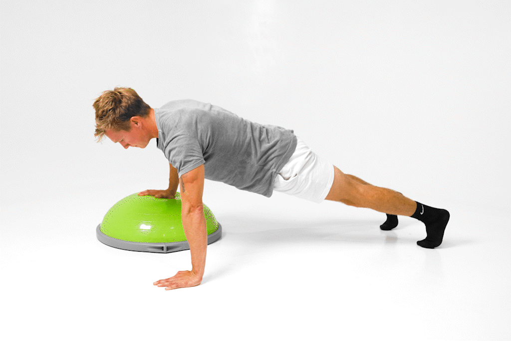 Man demonstrates BOSU Staggered Pushup with one hand on the ball and the other on the ground.