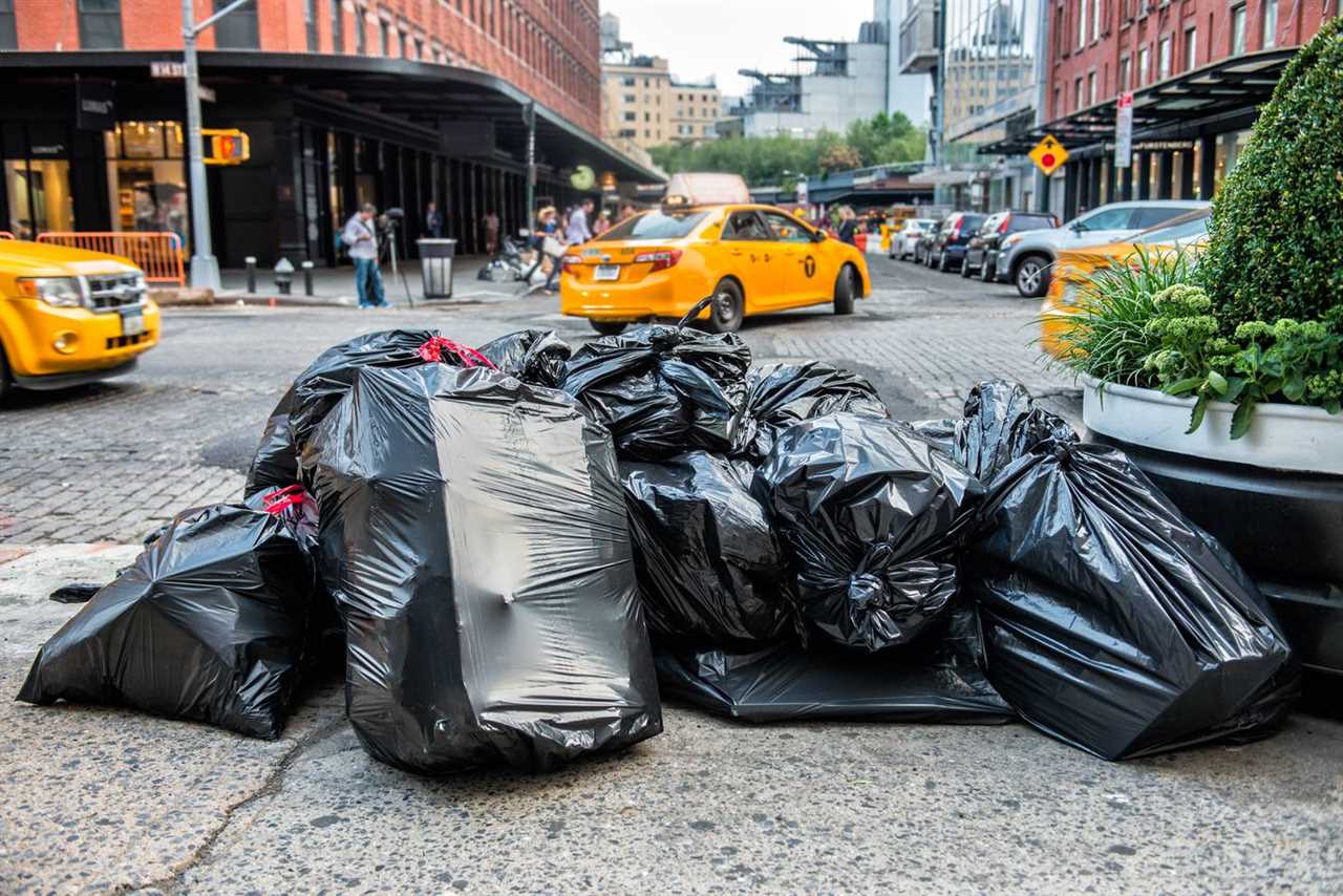 Filled black garbage bags on curb waiting to be picked up by NYC sanitation workers.