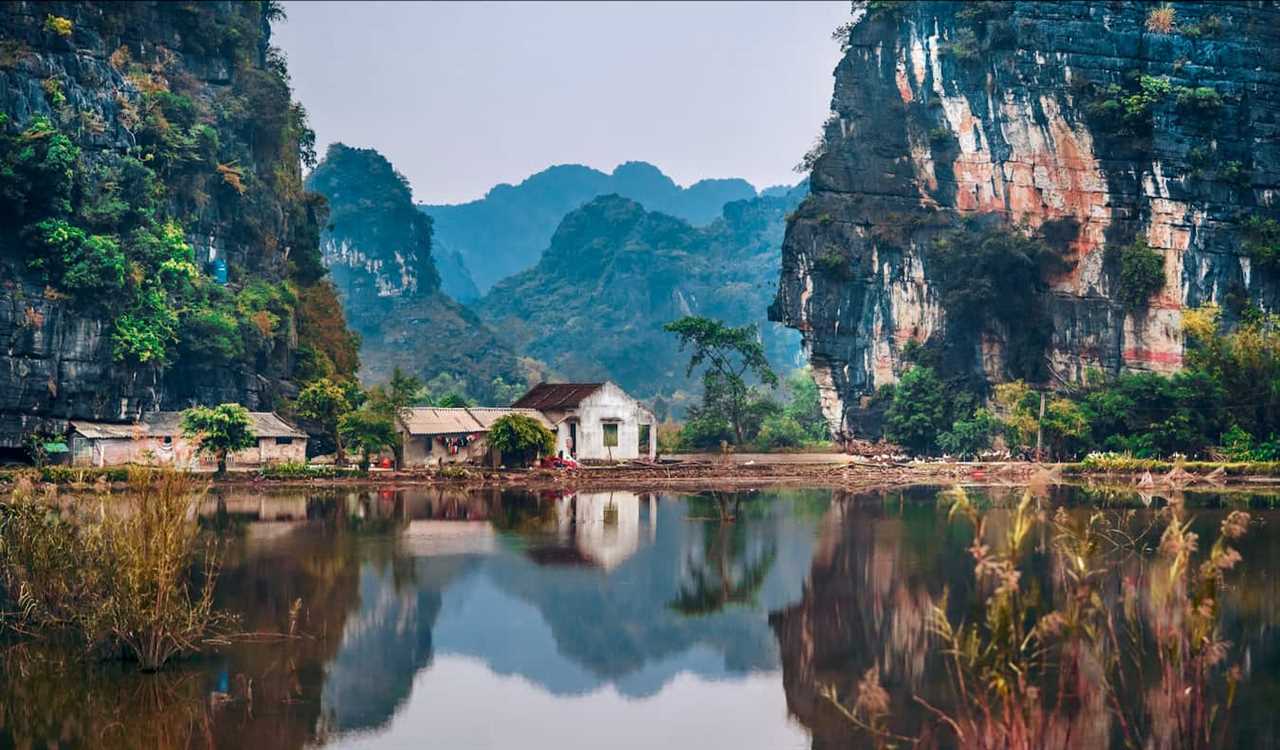 A small building nestled against the mountains near a lake in rural Vietnam