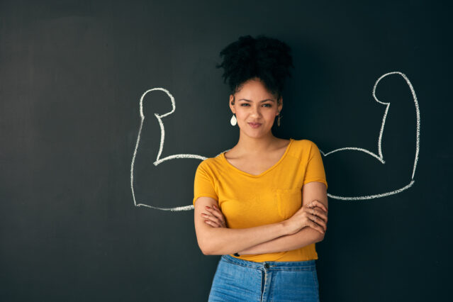 Woman posing with a chalk illustration of flexing muscles against a dark background.