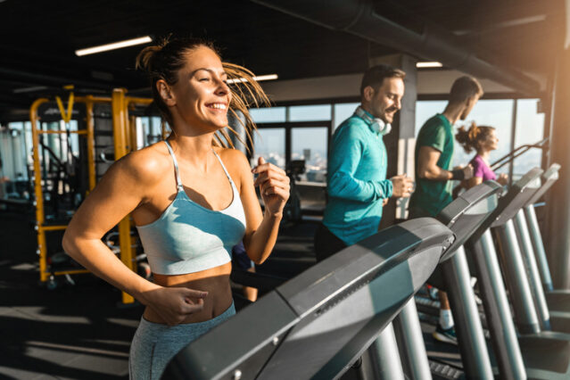 Happy people jogging on treadmills in a health club