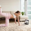 Woman in athletic gear working out in her living room with an online fitness program