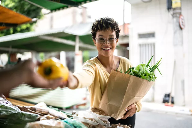 Woman buying diverse plant foods at farmers market
