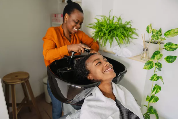Woman washing another woman's natural dry hair for moisture