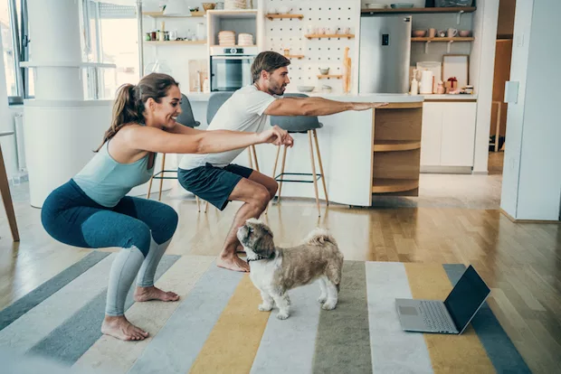 Couple doing squats and the best pelvic floor exercises at home with dog
