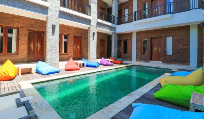 Long, emerald-colored pool surrounded by colorful bean bags in an inner courtyard at Gelatik Bed & Breakfast in Seminyak, Bali