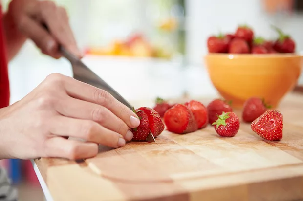 Woman slicing strawberries to help with PMS