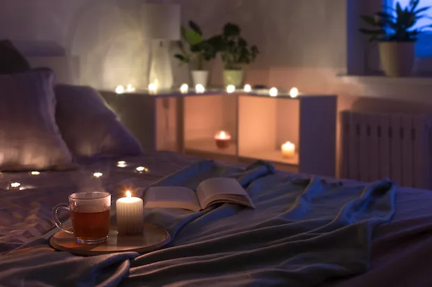 Cozy bedroom at night with candles and tea; sleep astrology concept