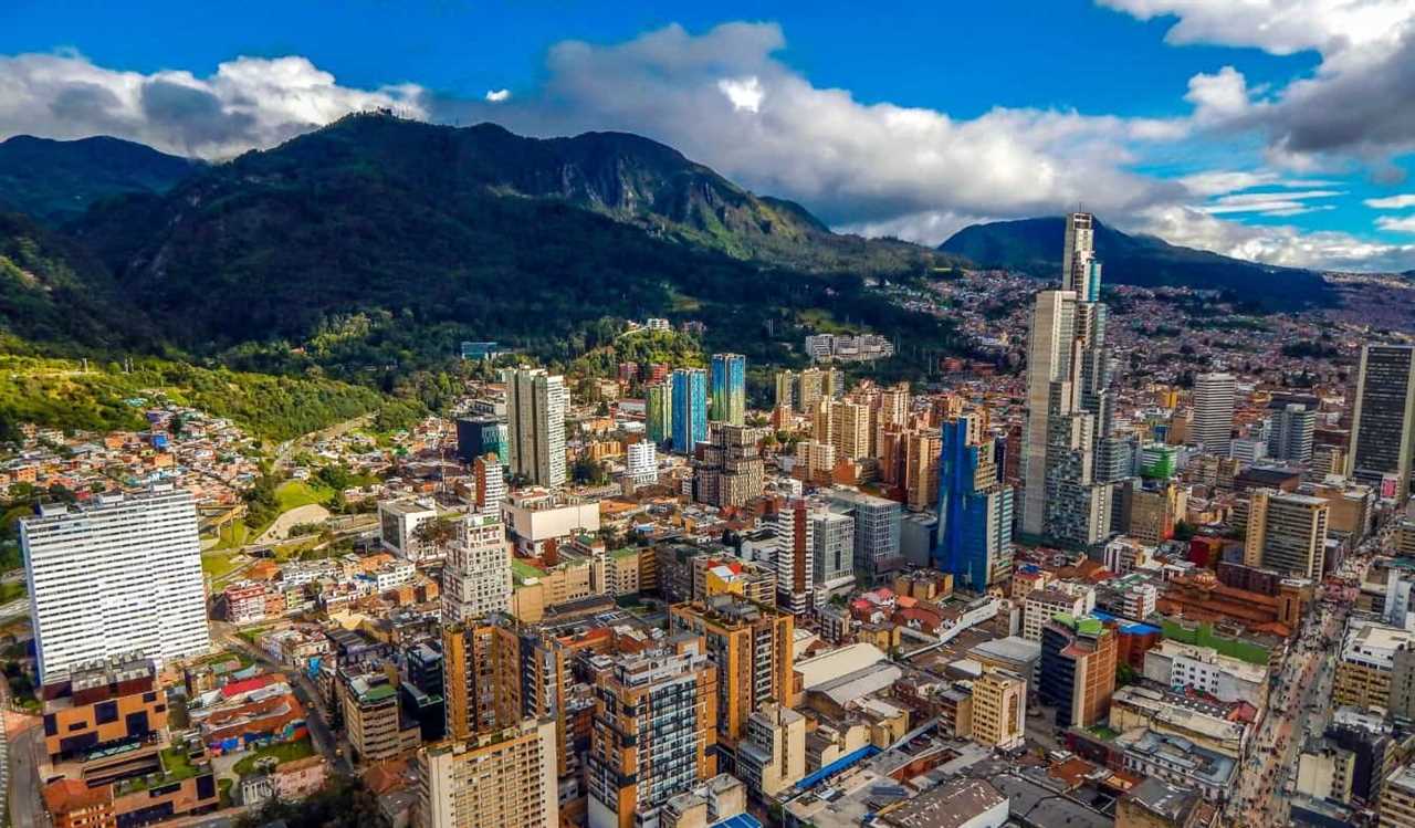The skyline of Bogota, Colombia, with tall skyscrapers next to lush green mountains