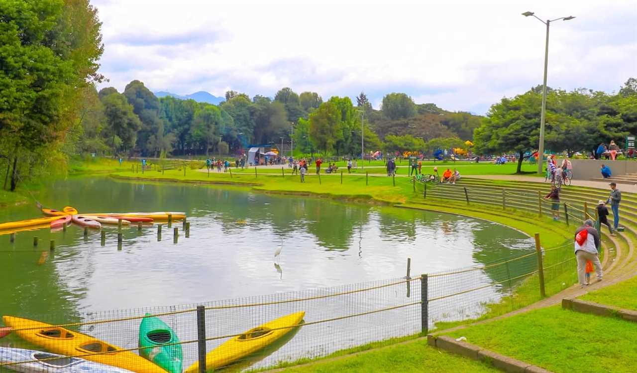 Kayaks floating in a lake, surrounded by people walking and running, at Simon Bolivar Park in Bogotá, Colombia