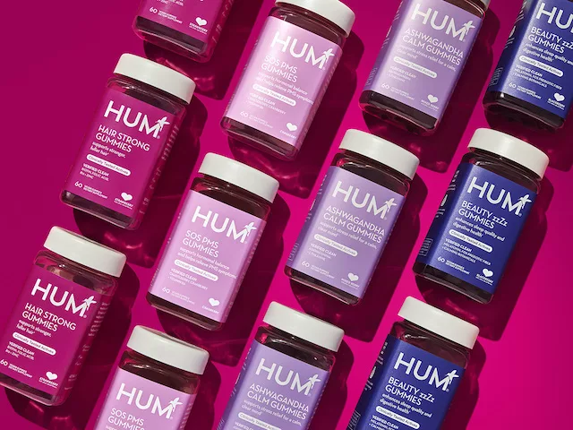 HUM gummy supplements on a pink background