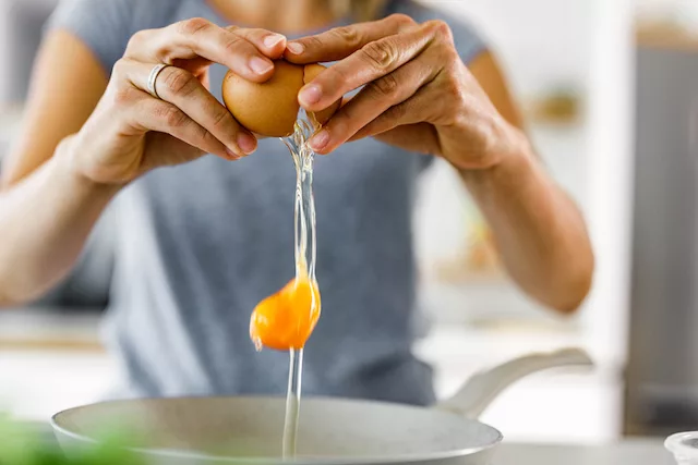 Woman cracking an egg for breakfast to lose weight with protein