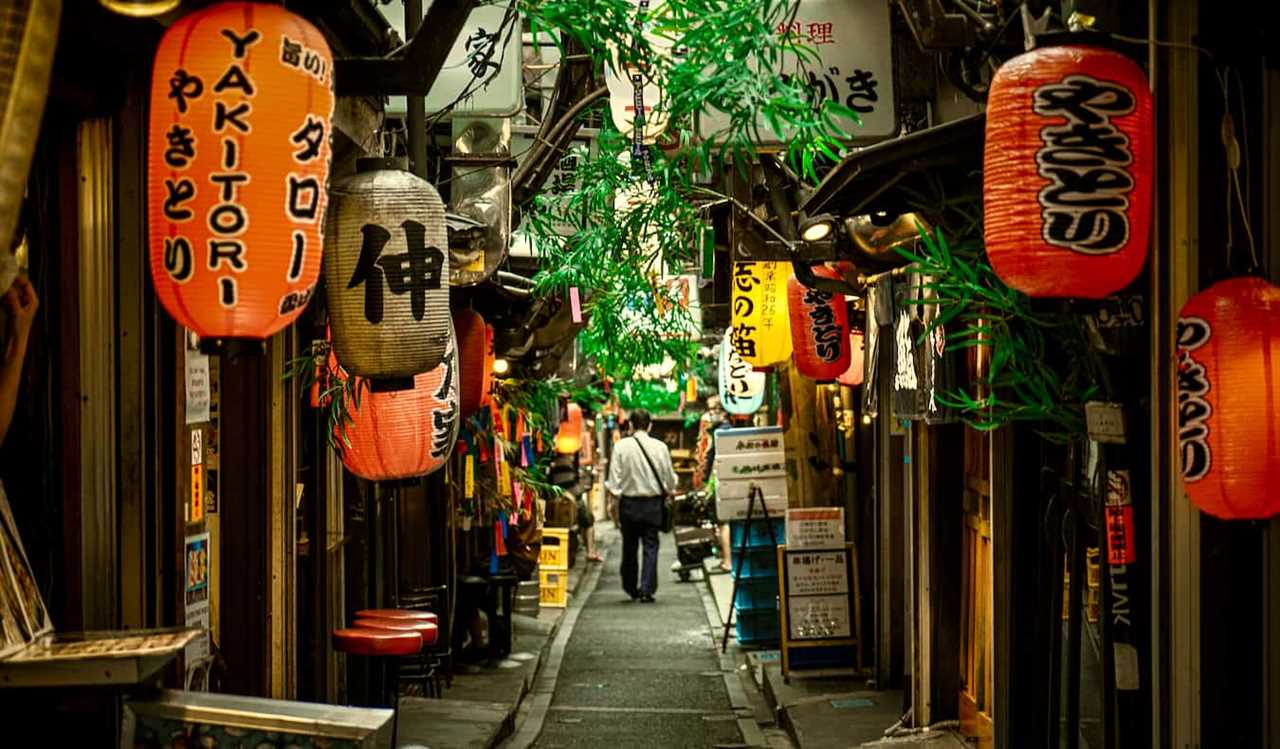 A traveler exploring a dim, narrow alley in the Shinjuku area of Tokyo, Japan