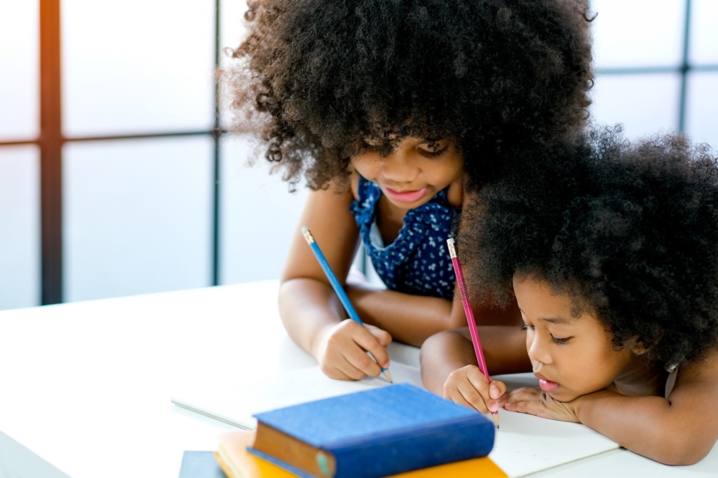 two cute black girls looking at a book on a desk