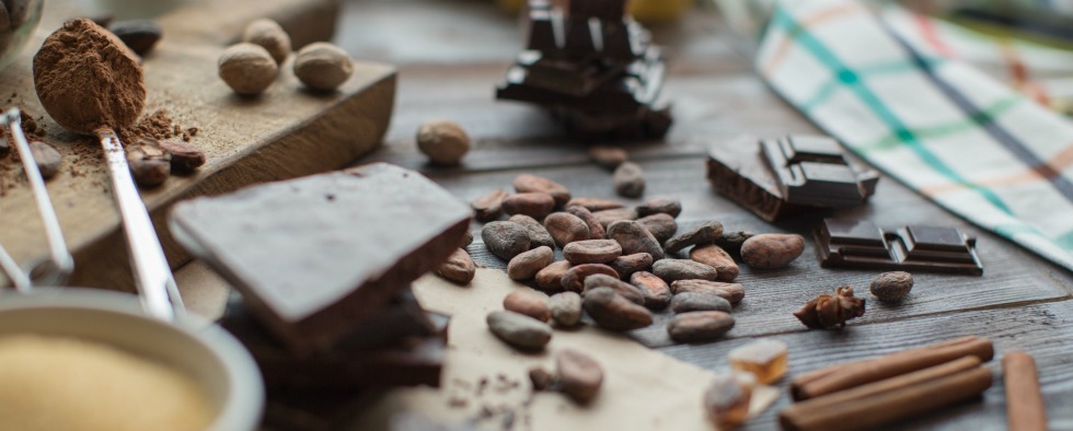 cocoa beans, spices and pieces of chocolate on the wooden table