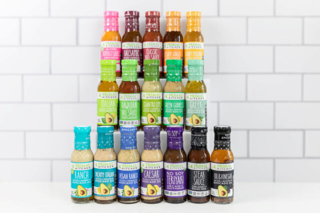 Primal Kitchen dressings and sauces arranged in a pyramid in front of a white tile background.