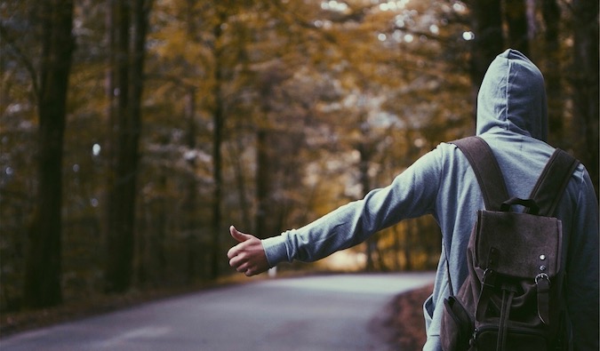 A man in a grey shirt hitchhiking