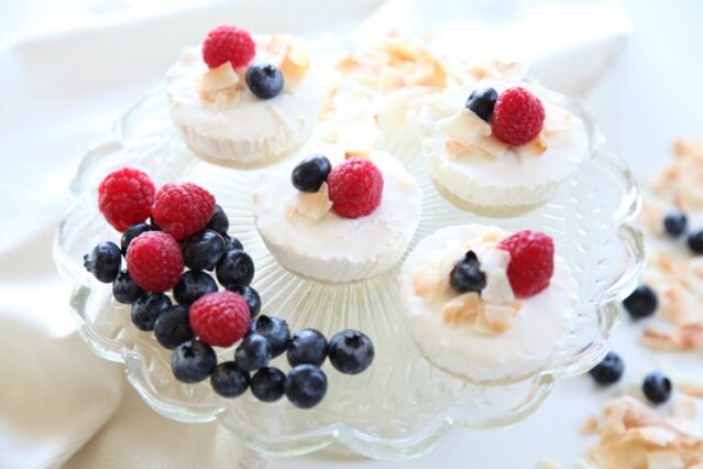 Crystal stand with four cheesecake bites and fresh blueberries and raspberries.