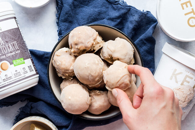 Keto ice cream bonbons in a bowl with a hand reaching in to grab one.